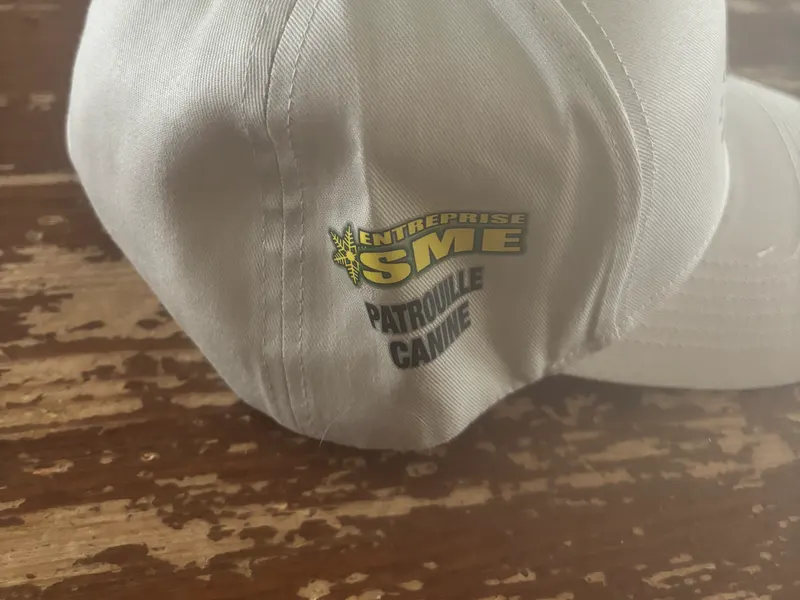 Côté de la casquette portant les logos Entreprise SME et Patrouille canine