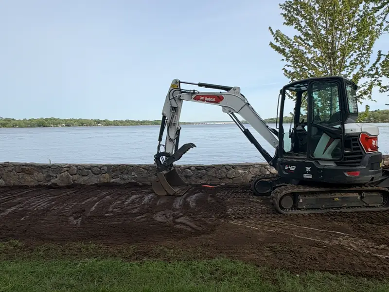 Pelle compacte Bobcat au travail sur un terrain au bord de l'eau