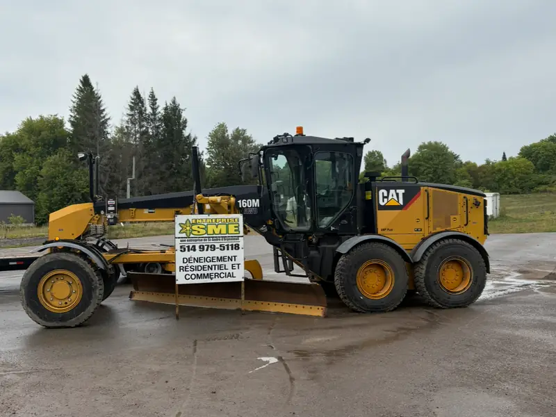 Niveleuse CAT 160M portant la pancarte de l'Entreprise SME, déneigement résidentiel et commercial