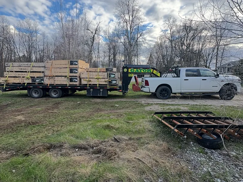 Caisses de bois empilées et sanglées sur le fardier à col de cygne, camionnette RAM de l'Entreprise SME attelée